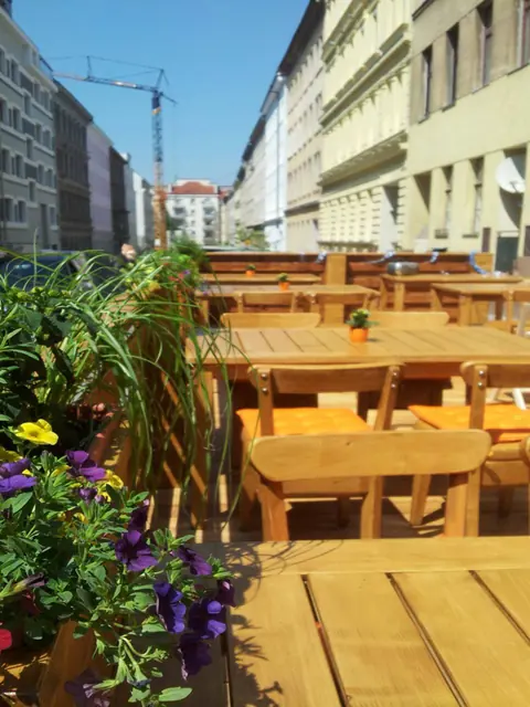 Gastgarten an der Wimmergasse mit Holztischen und Blumen