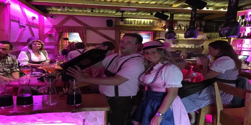 Gäste in Lederhose und Dirndl tanzen an der Bar